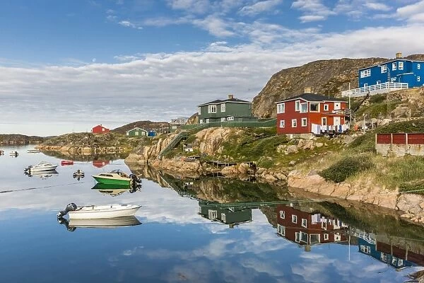 Calm waters reflect the brightly colored houses in Sisimiut, Greenland, Polar Regions