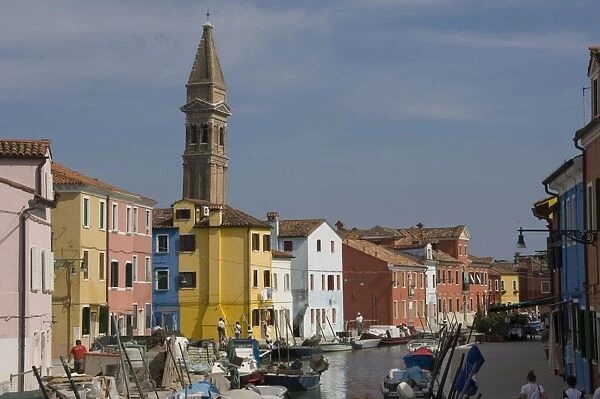 A canal with pastel painted houses and the leaning tower of San Martino