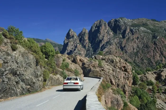 Framed Print : Car on mountain road above the Spelunca Gorge, with Capo Ferolata behind Framed Print : Car on mountain road above the Spelunca Gorge, with Capo Ferolata behind