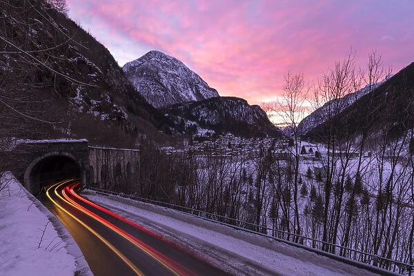 Car trail lights on the icy road at dawn, Campodolcino, Spluga valley, Sondrio province
