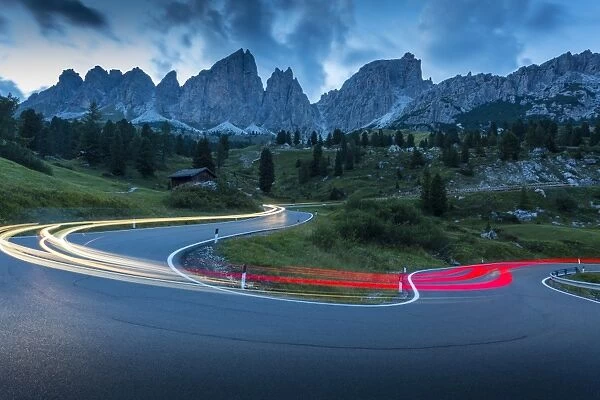 Car trail lights on Passo Pordoi with mountain backdrop at dusk, Province of Bolzano