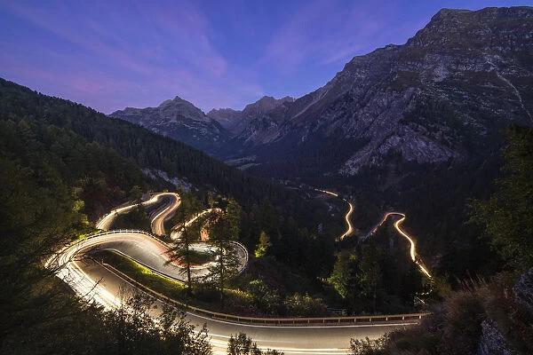 Car trails lights on narrow bends of Maloja Pass mountain road, Engadine, Canton of