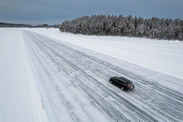 Car traveling on ice track on a frozen lake in the snow covered landscape, Jokkmokk, Norrbotten, Lapland, Sweden, Scaninavia, Europe