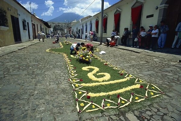 Carpet of plants and flowers being laid on a street for one of the Easter processions