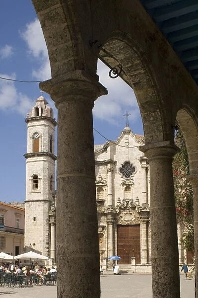 Catedral de San Cristobal and a cafe viewed through the arches of an arcade in the Plaza de la Catedral, Habana Vieja (old town), Havana, Cuba, West Indies