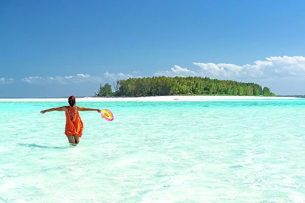 Cheerful woman with arms outstretched standing in the turquoise sea, Zanzibar, Tanzania, East Africa, Africa
