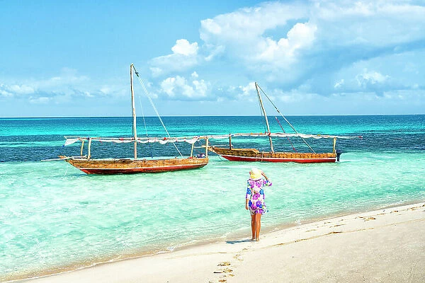 Cheerful woman with hat admiring the crystal clear sea standing on a beach, Kwale Island, Zanzibar, Tanzania, East Africa, Africa
