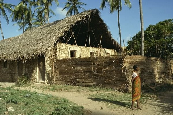 Child stood before traditionally built home