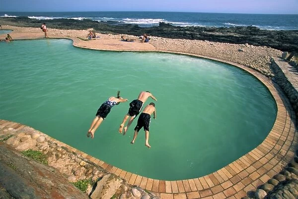 Three children diving into a swimming pool
