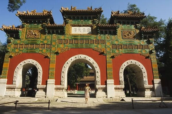 Chinese girl under a glazed archway at the Confucius Temple Imperial College built in 1306 by the grandson of Kublai Khan administering the official Confucian examination system, Beijing