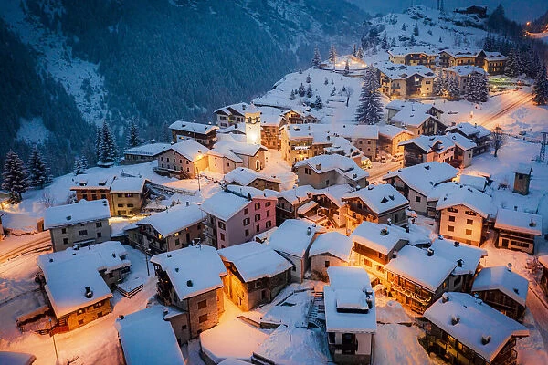 Christmas lights on mountain houses and chalets covered with snow at dusk, Pianazzo