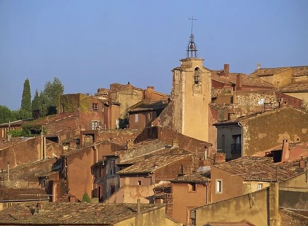 Church bell tower above the roofs of houses in the village of Roussillon in Provence