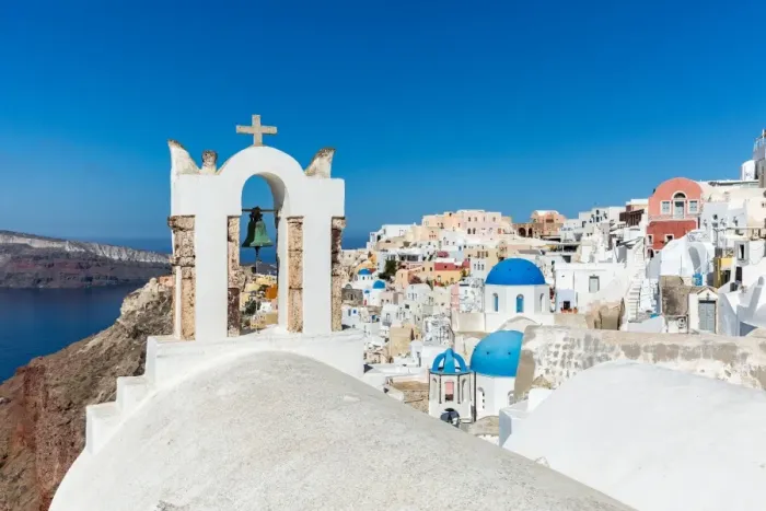 Framed Print : A church roof and bell with the white washed stone walls and blue church cupolas of Oia Framed Print : A church roof and bell with the white washed stone walls and blue church cupolas of Oia