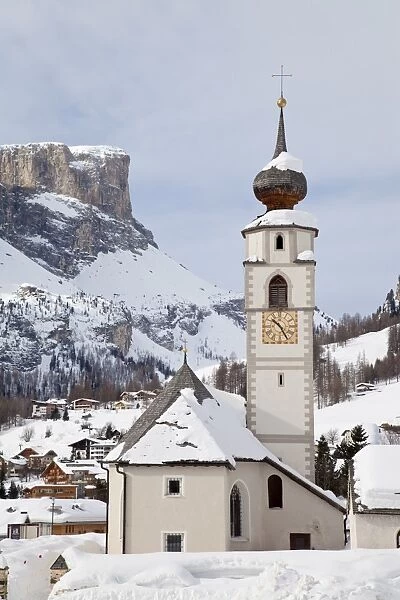 The church and village of Colfosco in Badia, 1645m, and Sella Massif range of Mountains under winter snow, Dolomites, South Tirol, Trentino-Alto Adige