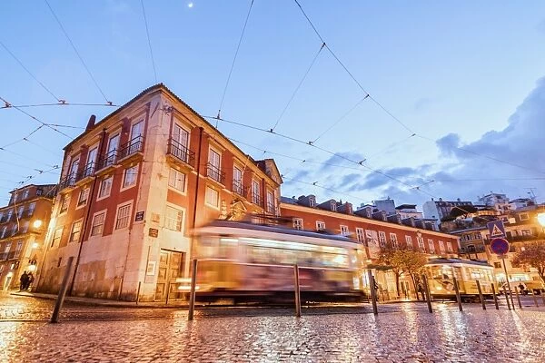 City lights on the typical architecture and old streets at dusk while the tram 28 proceeds