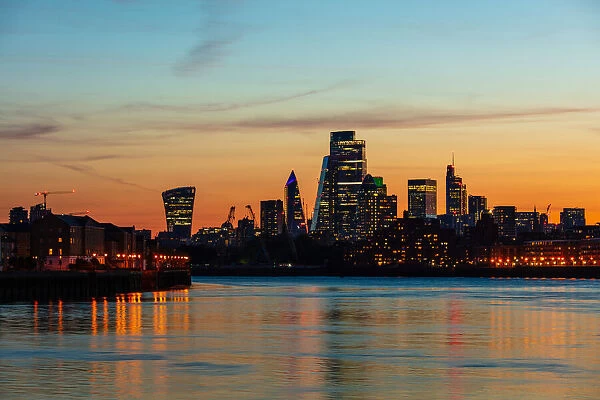 The City of London skyline at sunset reflecting in River Thames, London, England, United Kingdom, Europe