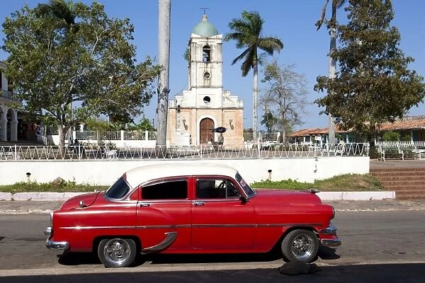 Classic red American car parked by the old square in Vinales village, Pinar del Rio