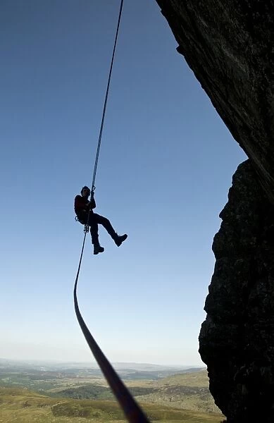 A climber abseiling from a cliff in the Ogwen Valley, Snowdonia, North Wales