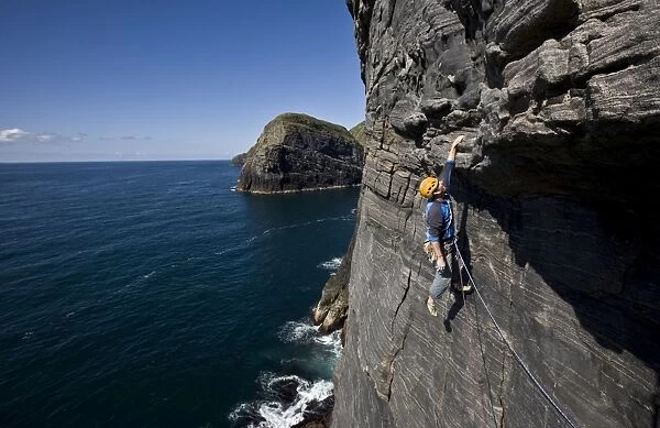 A climber hangs above the sea on the huge west face of Dun Mingulay cliff