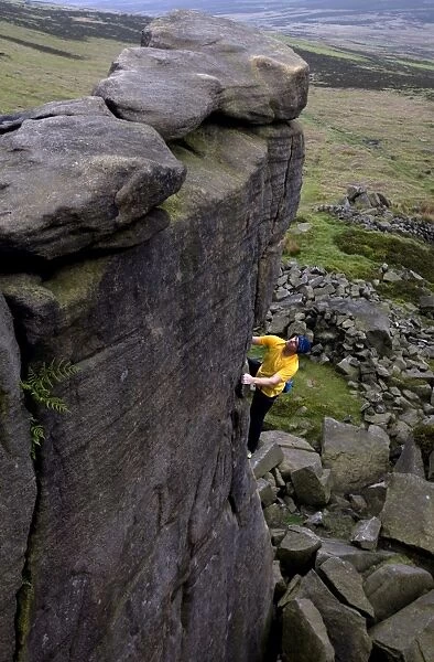 Climber makes a solo ascent of one of the thousands of classic outcrop climbs on the popular cliff of Stanage Edge, near Hathersage, Peak District, Derbyshire, England, United