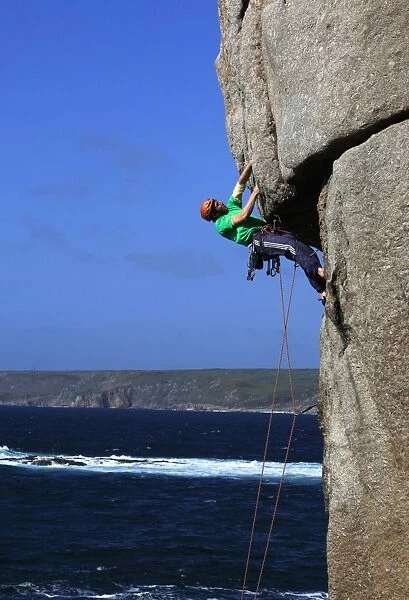 A climber tackles a difficult overhang on the cliffs near Sennen Cove, a popular rock climbing area at Lands End, Cornwall, England, United