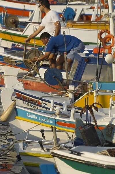 Close up of row of fishing boats in harbour with two men on board