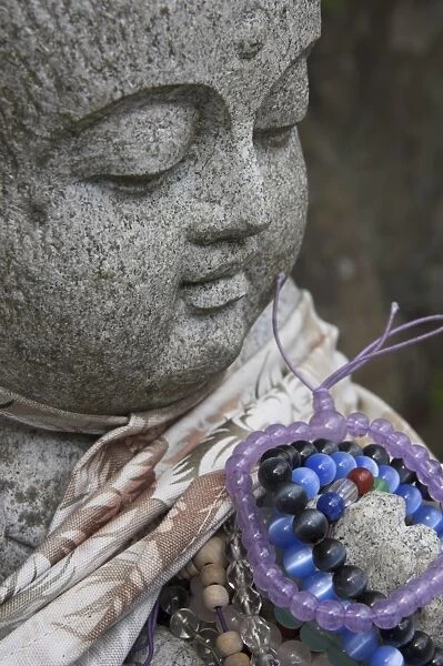 Close up of a traditional stone figure with prayer bracelets