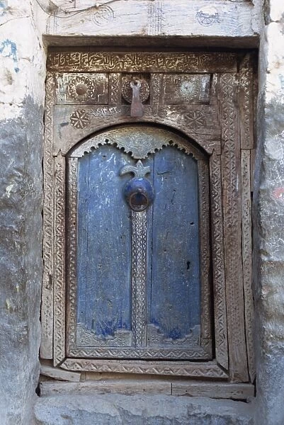 Close-up of a blue door in a carved wood frame in the