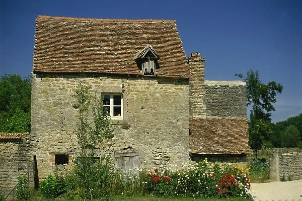 Close-up of exterior of a stone house, with cracked walls, and a flower bed