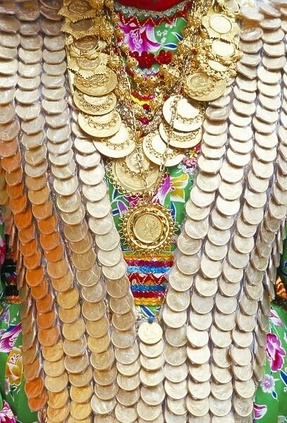 Close-up of a girls dress decorated with old gold coins