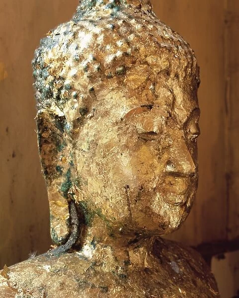 Close-up of the head of a statue of the Buddha covered in gold leaf