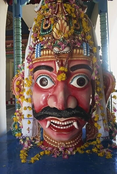 Close-up of statue with wide eyes and fangs at Sri Mariamman temple