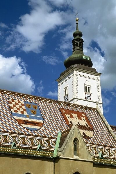 Close-up of tile roof with pattern of shields and clock tower of St. Marks church