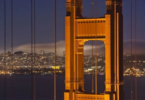 Closeup view of the north tower of the Golden Gate Bridge at sunset with the San Francisco city skyline, San Francisco, California, United States of America