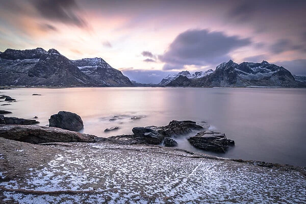 Clouds at dawn over the cold sea and Vareid beach covered with snow, Flakstad, Nordland county, Lofoten Islands, Norway, Scandinavia, Europe