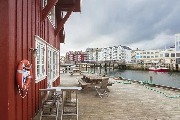 Clouds frame the typical wooden houses of the fishing village surrounded by sea, Svolvaer