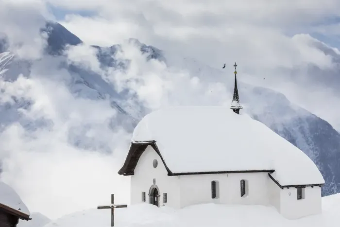 Framed Print : Clouds above the mountain huts and church covered with snow, Bettmeralp, district of Raron Framed Print : Clouds above the mountain huts and church covered with snow, Bettmeralp, district of Raron