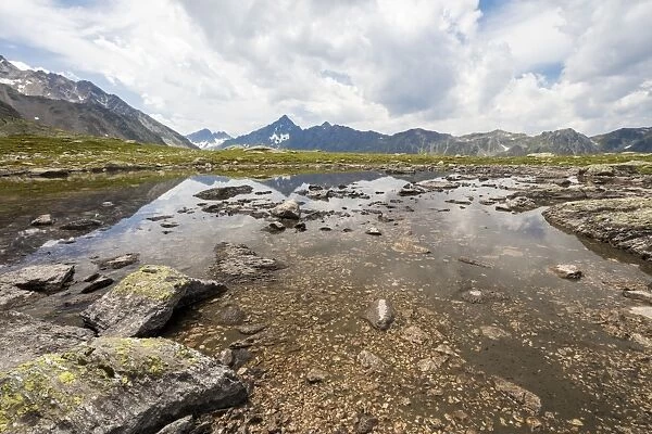 Clouds on rocky peaks reflected in the alpine Lake Schottensee, Fluela Pass, canton of Graubunden
