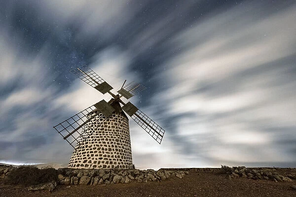 Clouds in the starry sky over a traditional windmill, La Oliva, Fuerteventura