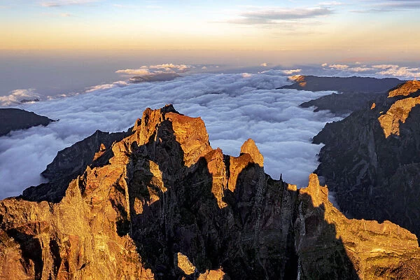 Clouds surrounding the rocky peak of Pico das Torres lit by sunset, Madeira island