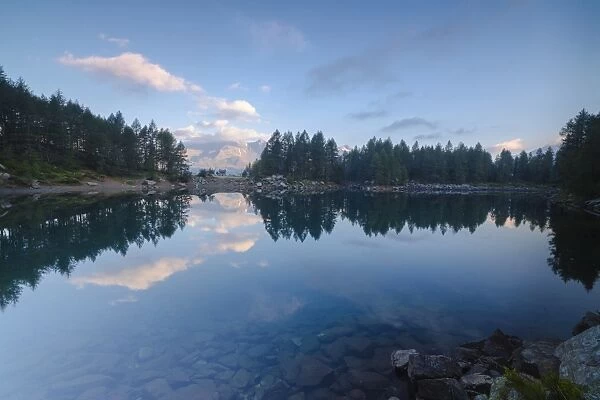 Clouds and woods reflected in Lago Azzurro at dawn, Motta Madesimo, Spluga Valley