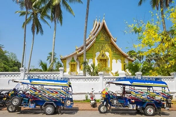 Colorful tuk-tuks in front of Haw Pha Bang temple on the grounds of the Royal Palace
