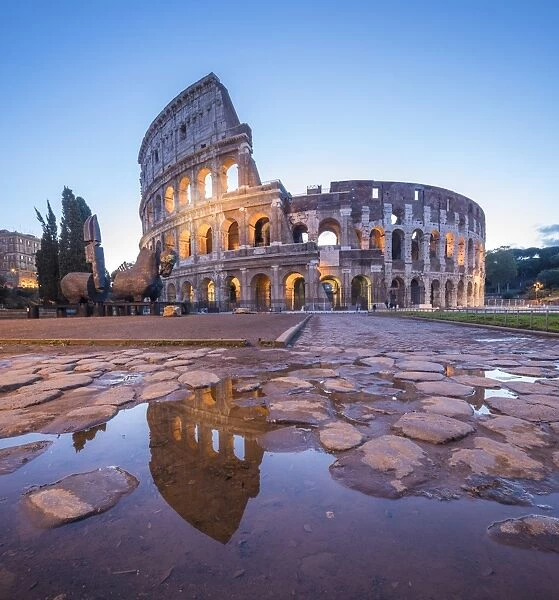 The Colosseum (Flavian Amphitheatre), UNESCO World Heritage Site, reflected in a puddle at dusk