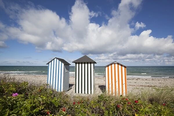 Colourful beach huts on pebble beach with blue sea and sky with clouds, Rageleje