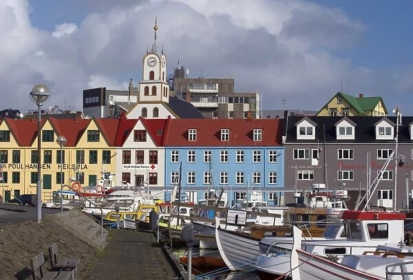 Colourful boats and picturesque gabled buildings along the quayside in Vestaravag harbour
