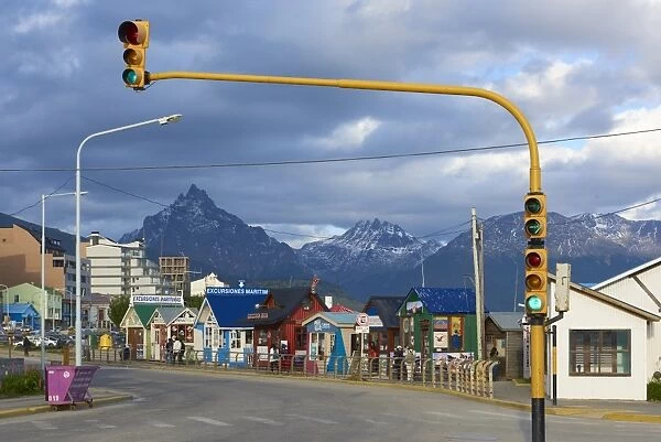 Colourful houses on touristic road framed by traffic lights post with snowy mountain chain beyond