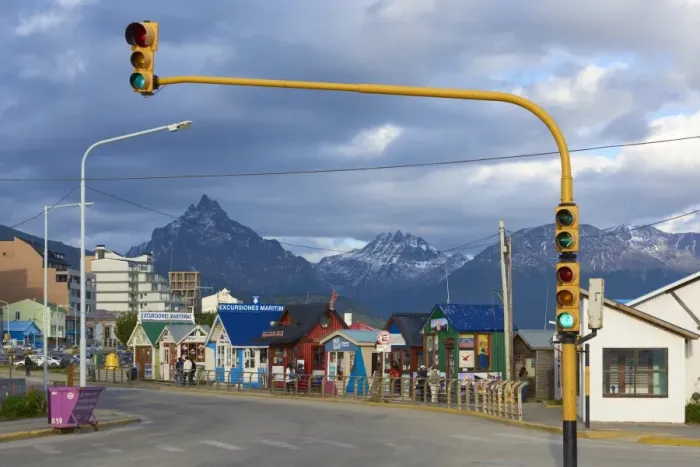 Framed Print : Colourful houses on touristic road framed by traffic lights post with snowy mountain chain beyond Framed Print : Colourful houses on touristic road framed by traffic lights post with snowy mountain chain beyond