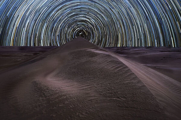 Concentric circumpolar star trail above sand dunes in the Rub al Khali desert, Oman