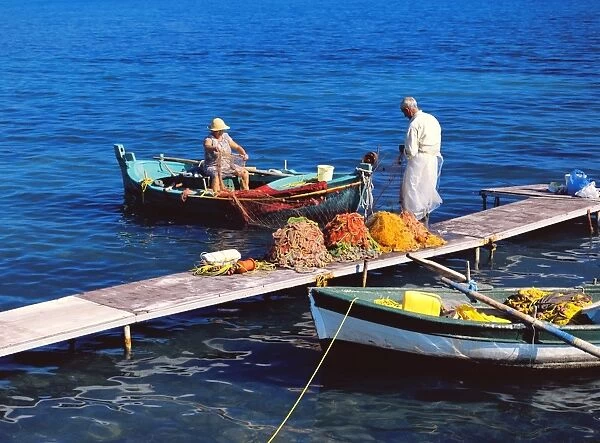 Corfou. Fisherman and his wife cleaning the fishing nets in boat