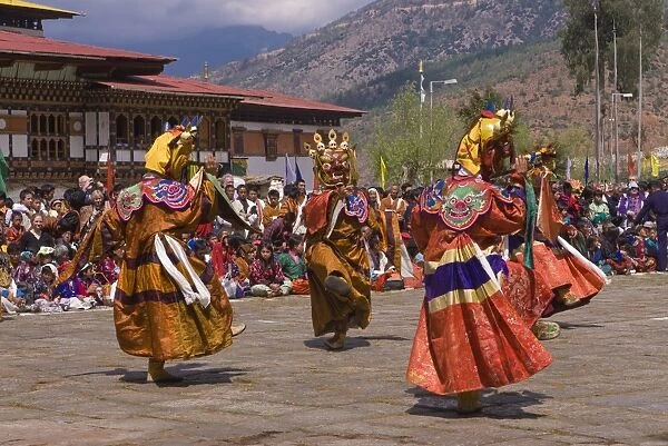 Costumed dancers at religious festival with many visitors, Paro Tsechu